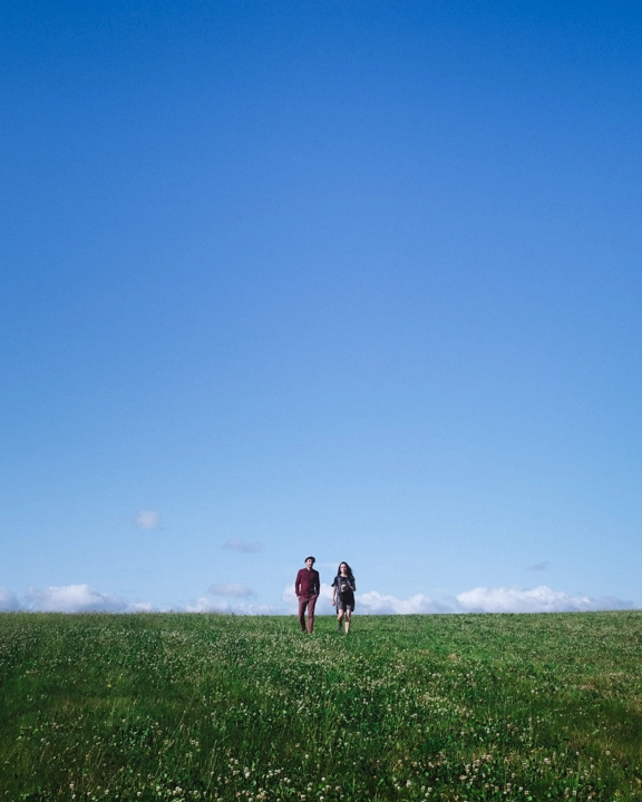 Deux personnes au milieu d'un champ d'herbe verte, devant un ciel bleu, image de Ken Lecoq, photographe basé entre Nantes et Machecoul.