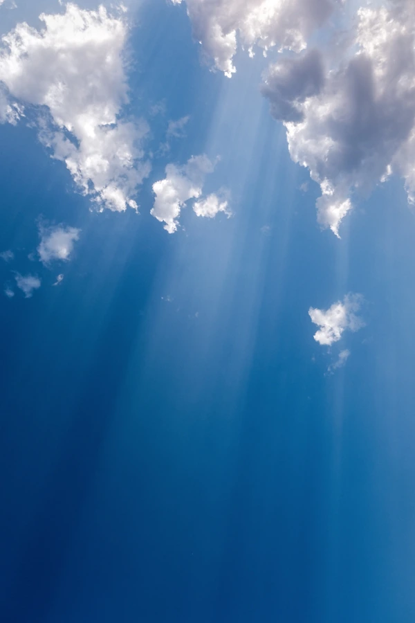 Photo d'un ciel bleu intense avec des nuages blancs laissant traverser la lumière du soleil, lors d'un été à Nantes en Loire Atlantique.