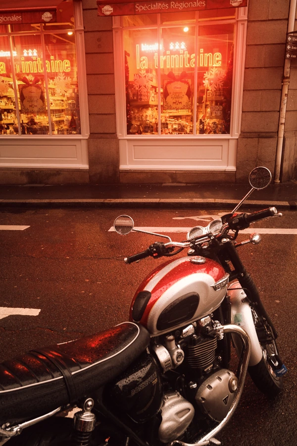 Image d'une rue de Nantes avec une moto rouge et noir devant la boutique "La Trinitaine", photographié par un photographe pro.