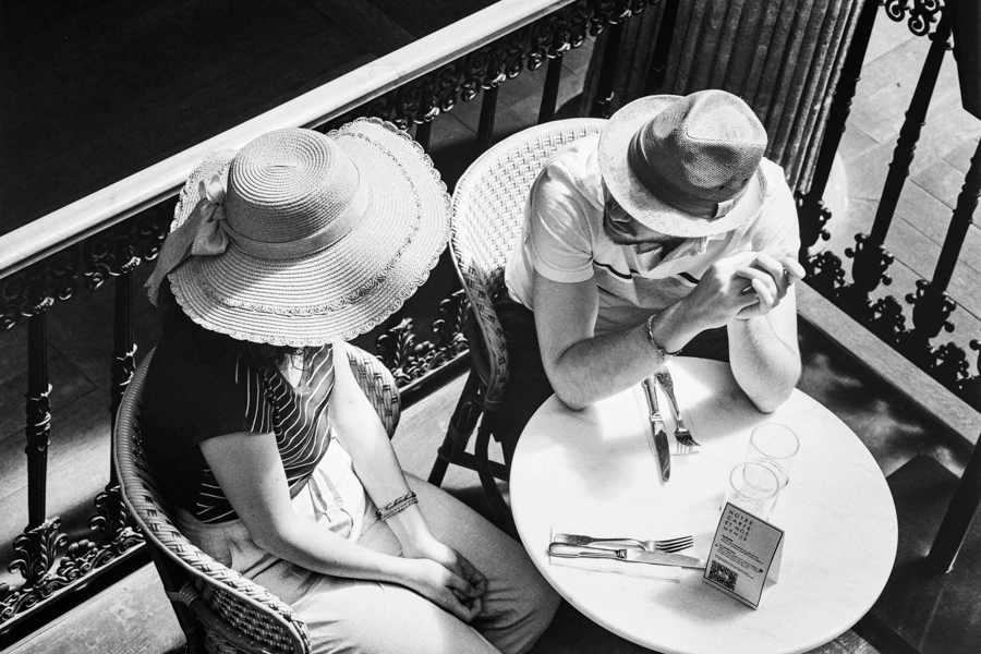 Photo noir et blanc de deux personnes portant des chapeaux, assis à une table dans le passage Pommeraye à Nantes.
