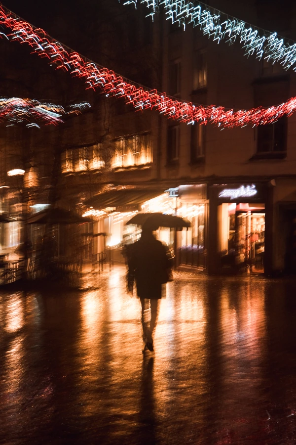 Photo de flou artistique d'une rue de Nantes la nuit, avec une personne tenant un parapluie, par le photographe Ken Lecoq.