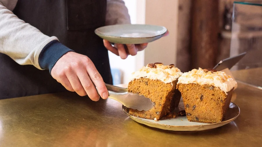 Serveur saisissant un carotte cake avec une pince, photo issue d'un reportage photo professionnel pour site internet et communication d'entreprise.